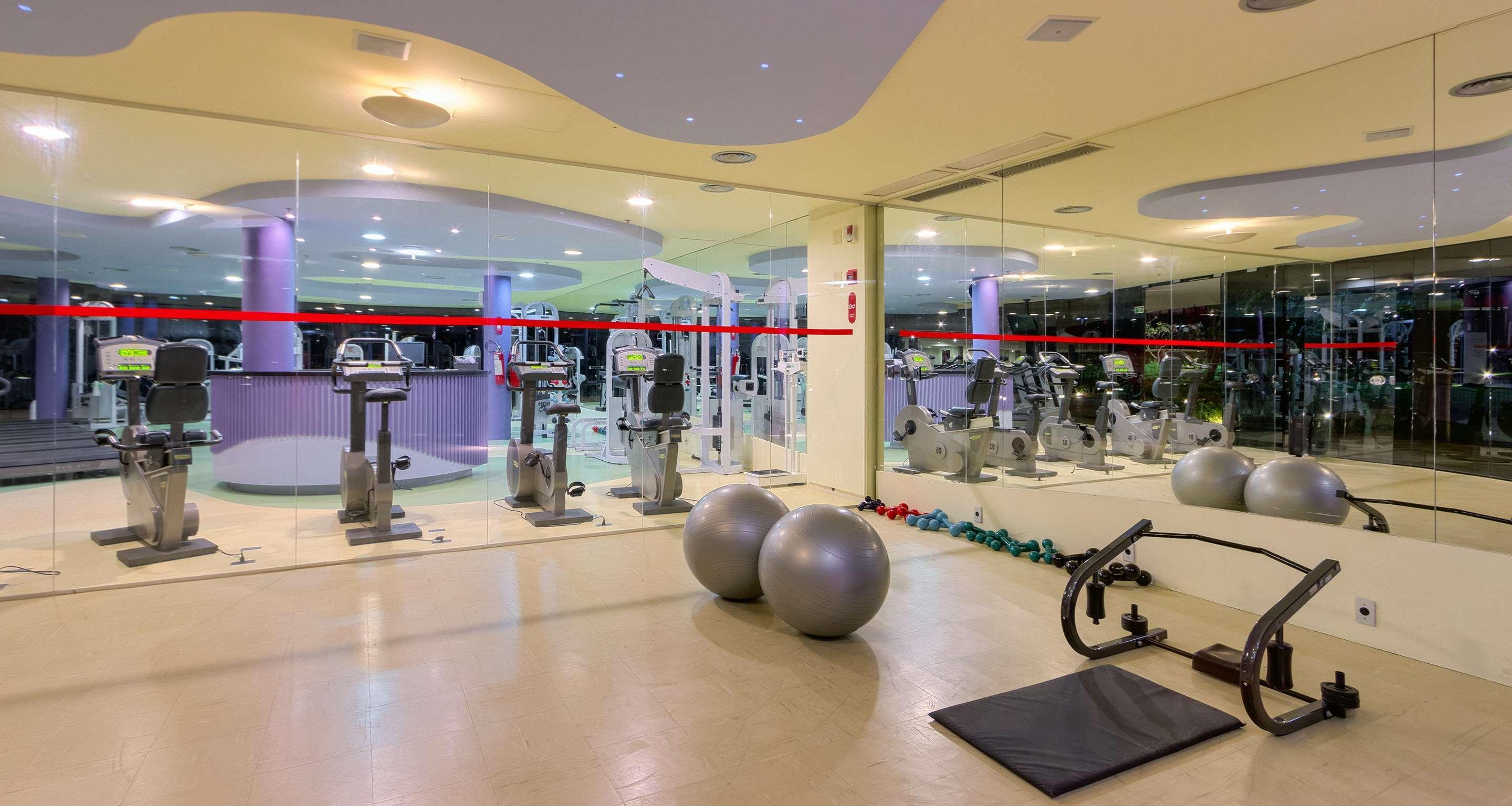 Royal Tulip Brasilia Alvorada Hotel ภายนอก รูปภาพ The photo depicts a gym or fitness area. In the foreground, there are two large exercise balls and a mat on the floor. Behind them, there is a wall of mirrors that reflects various gym equipment, including exercise machines and bikes. The lighting in