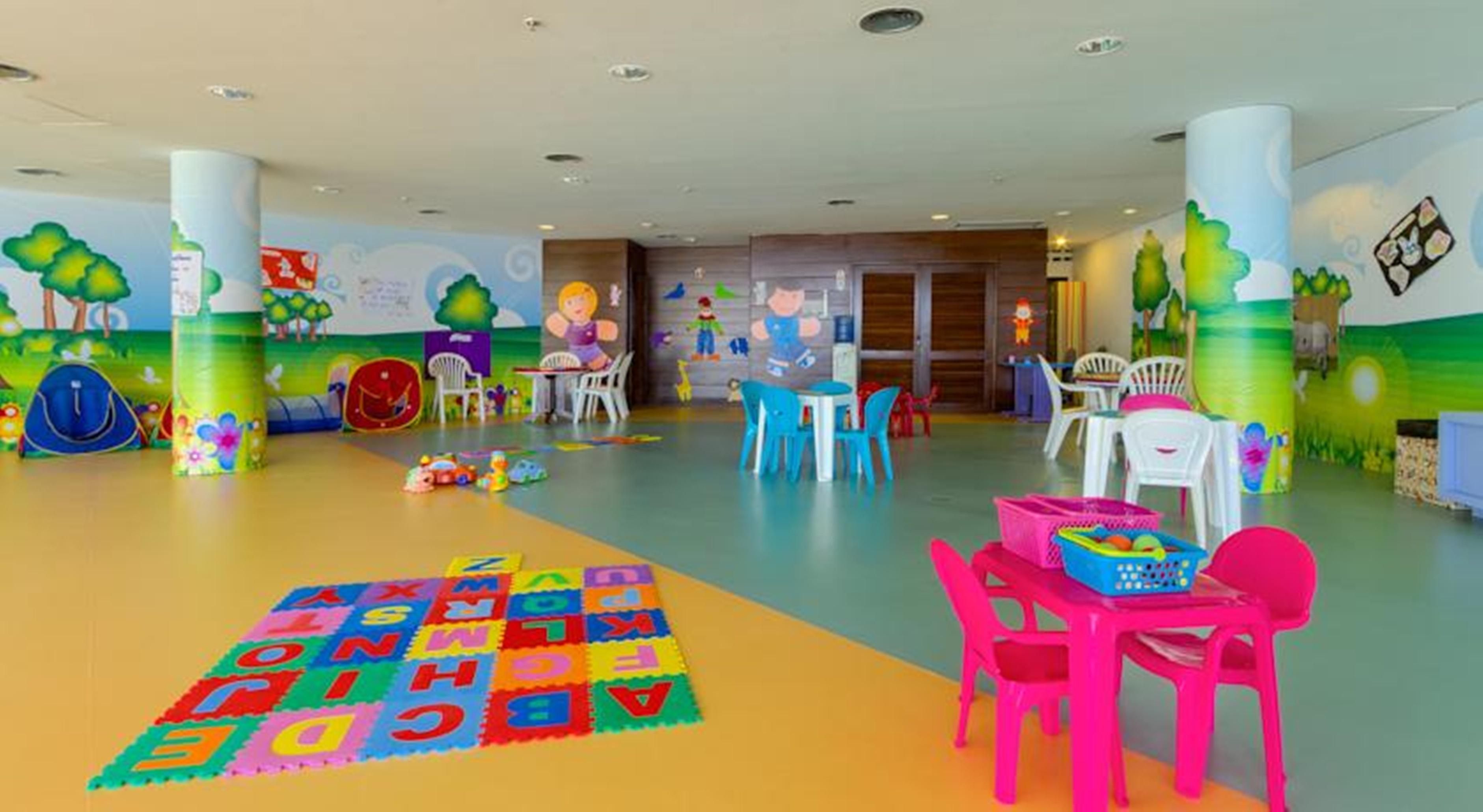 Royal Tulip Brasilia Alvorada Hotel ภายนอก รูปภาพ The photo shows a colorful and spacious children's playroom. The floor is divided into sections with different colors, and there is a large play mat featuring letters and numbers. 

In the room, there are several small, lightweight tables and chairs 